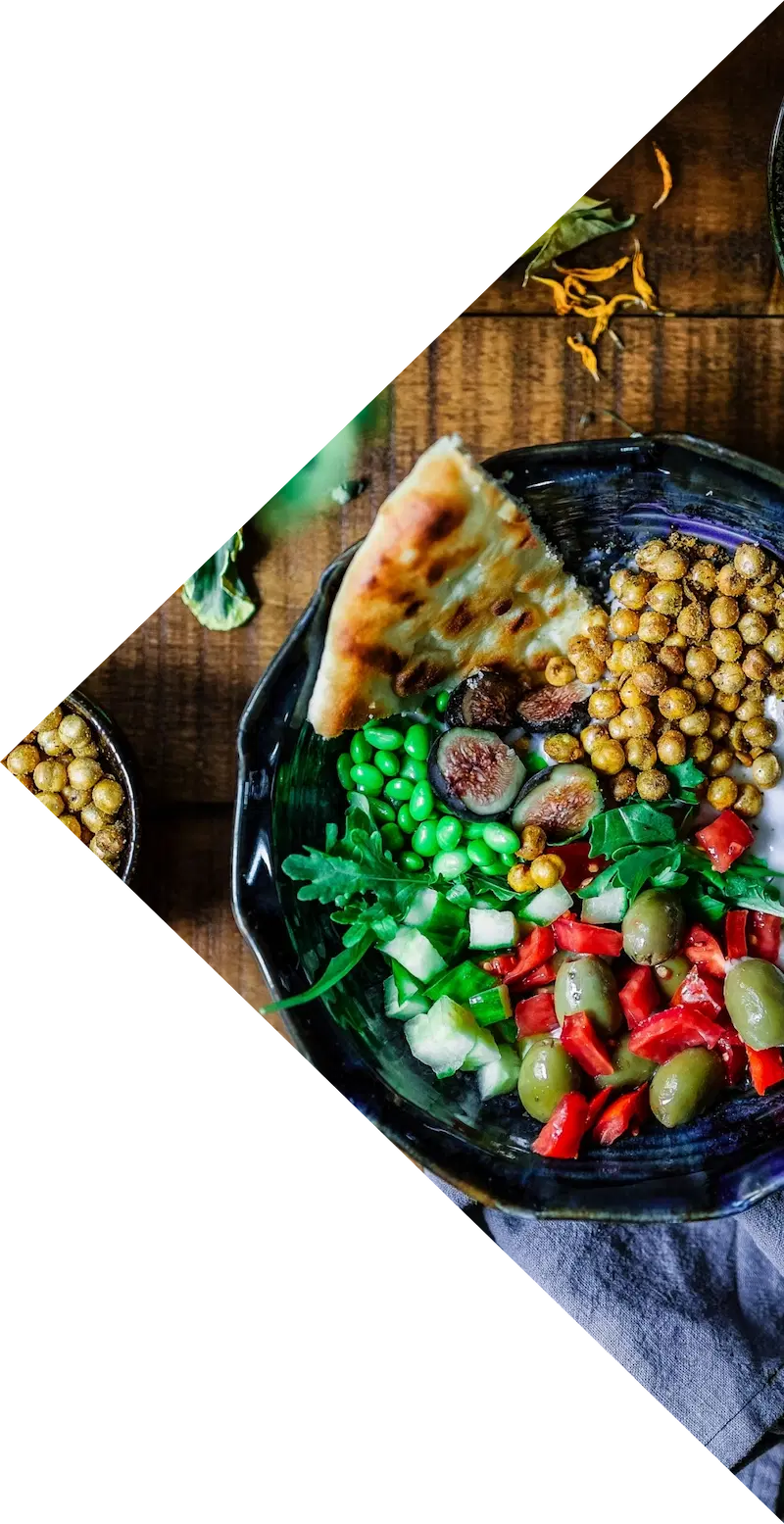 Insalata con ceci, fichi, olive e verdure in una ciotola su un tavolo di legno